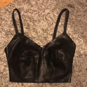 Croppad skinntopp  - Säljer denna jättecoola topp i skinnimitation från Zara då den är förstor på mig. Den är aldrig använd så i helt nytt skick! Skulle passa perfekt på fest🤩