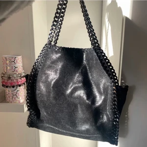 Superfin stella liknande väska - Superfin svart skimrig/glittrig väska med kedjor som liknar Stella McCartney väskan. Passar till allt och får plats med det mesta! Jättefint skick! Skriv i chatten för att buda! Högst bud:490kr+frakt eller köp direkt för 600kr+frakt🥰🥰