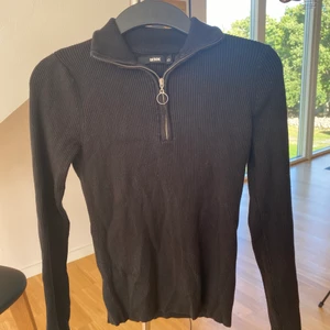 Svart polotröja med dragkedja  - Fin svart ribbstickad enkel polotröja från Bikbok. Heltight med en dragkedja ner vid halsen, se bild. Använd fåtal gånger. Inget fel på den. 