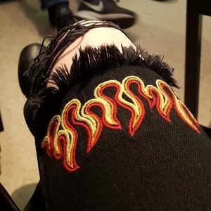 Jeans med eldsflammor från NA-KD stl.34 - Ett par coola jeans i en ”urtvättad” svart färg med eldsflammor som tyvärr blivit för små. Mått ca 66cm i midjan och 67cm i innerbenslängd. (Avklippta för en kortare person så kolla måttet) Frakt 57kr eller avhämtning i Borås!