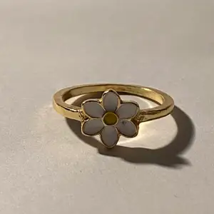 Silverring i form av en blomma med gulddetaljer.