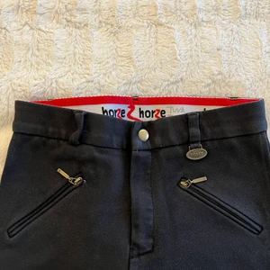 Ridbyxor - Säljer dessa svarta, helskodda ridbyxorna med kardborre spännen vid anklarna. Märket Horze och storlek 150!!