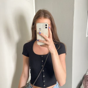 Svart T-Shirt  - Svart tröja med ihopsydda knappar framtill. Säljer då jag har en nästan likadan! 