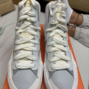 NIKE BLAZER MID x SACAI white/grey  - Säljer ett par äkta Nike blazer mid x Sacai i färgen white/grey storlek 48.5 Helt nya, aldrig använda!! Säljs pågrund av att jag inte kunde lämna tillbaka. Finns kvitto! 