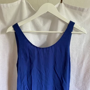 Djupblå långklänning - En fin långklänning i en underbar blå sidenimitation, och med snygg ryggdetalj. Klänningen är i perfekt skick, och med justerbar snörning som kan ändras efter tycke och smak. Fler bilder finns vid intresse. 