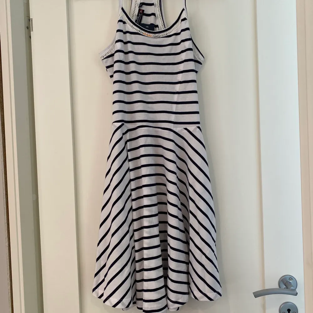 Vit, marinblå randig klänning från MARINE stl S oanvänd med prislappen kvar.  Klänningen går till ca knäna.                    (säljes för 50 kr ink frakt). Klänningar.