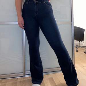 Superfina blåa utsvängda jeans i stretchmaterial. Har en fin blomdetalj på ena fickan där bak. Köpta på MCO, blomman är ditsydd själv.  FRAKT INGÅR! Storlek Medium, längd 32.