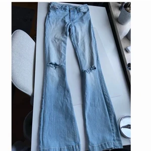 Ljusblå bootcut jeans - Ljusa mid waist bootcut jeans från cubus som jag stylat själv och klippt hål på. Strl W25, passar 34-36. Innerbenslängd: 85cm. Jag är 165 cm. Meddela för fler bilder. Budgivning från 170kr. Fraktkostnad tillkommer.