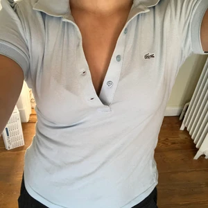 Piké / Tröja med krage - Säljer denna fina ljusblåa pikén / t-shirten med skitsnygg krage! Så mjuk och skön, perfekt färg och så snygg att ha både uppknäppt och stängd. Från Lacoste i storlek 36💗