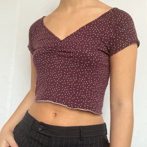 Croppat prickigt lila tshirt - Söt T-shirt med vita prickar. Avklippt nedtill. Plagget är i gott skick utan synliga Defekter och visas på en storlek S. Köpare står för 26kr frakt. 