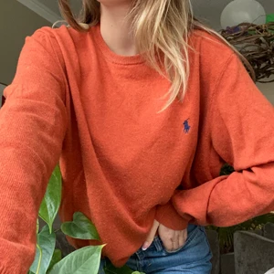 Ralph Lauren stickad tröja - En orange superskön tröja från Ralph Lauren! Storlek XL men sitter lagom oversized på mig som brukar ha S eller M i tröjor. Ett litet hål på vänstra ärmen därav ett sänkt pris, men det syns inte så mycket och går lätt att laga😊 Köparen står för frakten
