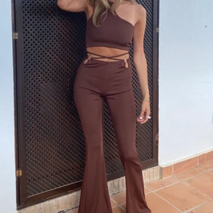 Brunt set - Brunt set i ribbat tyg, croptop och utsvängda långa byxor. Använt en gång, storlek S