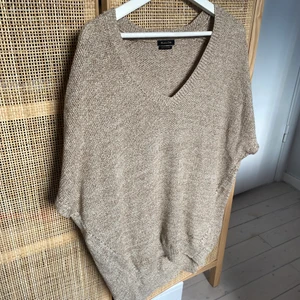 Beige väst/tröja med guld detaljer - En beige stickad väst/t-shirt med lite guldskimmer i. Från Massimo Dutti i gott skick, storlek XL. Snygg över en basic T-shirt eller en oversized skjorta.