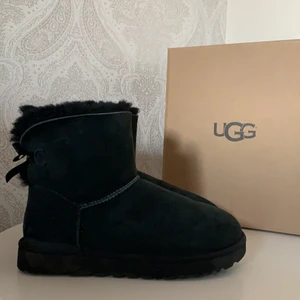 Mini Bailey Bow black Uggs  - Ett par jätte fina äkta uggs i modellen Mini Bailey Bow, dem är i jätte fint skick men säljer eftersom att jag köpte i en för stor storlek så dem är tyvärr alldeles för stora för mig, nypris är 2200 ⭐️ Kan mötas upp i Stockholm men annars står köparen för frakten!! 💞💞