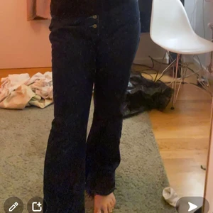 asfeta bootcut jeans - köpa secondhand, mörkblå jeans med ljusblå sömmar, igen dragkedja byxorna har knappar hela vägen upp, dem är inte lågmidjade men dem går ungefär under naveln.
