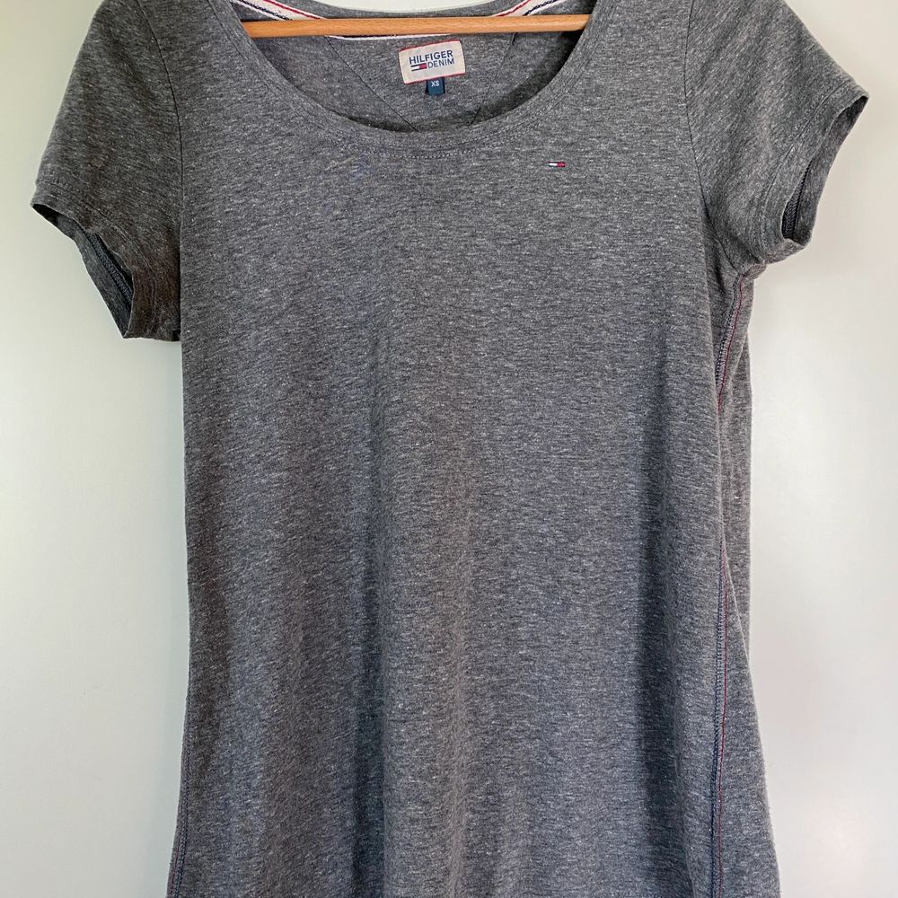 En klassisk grå t-shirt från Tommy Hilfiger, med märkets logga på framsidan. En perfekt grå färg👚 lite större än XS skulle jag säga, men samtidigt tajt i armarna på mig, som vanligtvis är en S✨Samfraktar gärna, men köparen står för frakten💕. T-shirts.