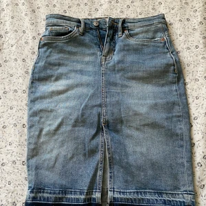 Jeanskjol - En superfin jeanskjol med slit fram. Går till precis över knäna på mig som är 164cm. Storlek 34. Formar sig fint runt höfterna! Bara att höra av sig för fler bilder!