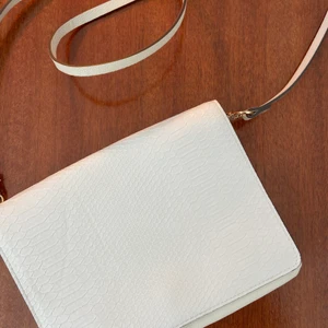 Väska Hm - Jätte fin ljus beige väska från hm med guldetaljer och ormskinnsmönster .Väskan  har två fack och långt axelband.