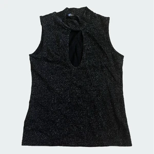 Svart glittrig topp med urringning  - Svart glittrig topp med 90 tals / 00 tals vibe och urringning där fram i storlek s