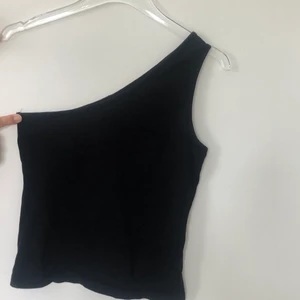 Svart one shoulder top - Säljer min svarta one shoulder top från Nelly som tyvärr är för stor. Strlk XS men mer som en S eller liten M skulle jag säga. Kan mötas upp i Sthlm, annars står köparen för frakten 💜💕
