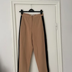Kostymbyxor & Other Stories strlk 36 - Beiga kostymbyxor med svarta ränder på sidorna. Använda ett fåtal gånger! 
