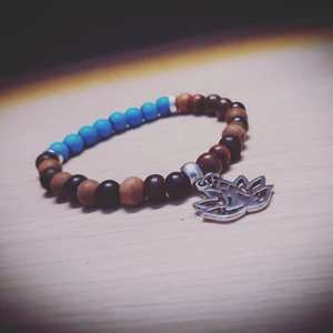 Armband - Tillverkas efter personligt mått. Strechband. Turkos Howlit, bruna Sandelträ och Jaspis. Lotus berlock.