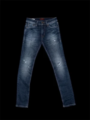 Blå slitna skinny jeans - Säljer ett par blå skinny jeans med slitningar och tvättade detaljer. Jeansen har fem fickor, dragkedjegylf och klassisk knapp. Materialet är denim med stretch för skön passform. Perfekta för en avslappnad och trendig look.