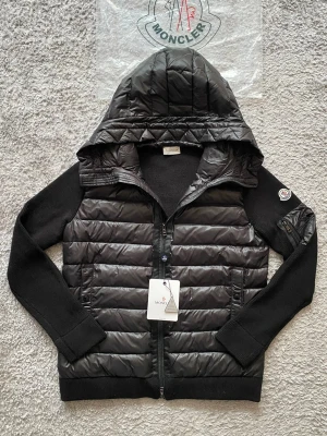 Svart Moncler cardigan -  Moncler cardigan i storlek L. Perfekt när du vill vara “casual” men ändå 10/10.  • Storlek L • Svart, klassisk modell • NFC-tag för äkthetsverifiering • Mycket fint skick  Funkar lika bra till jeans som till mer uppklätt. En sån där jacka man alltid slänger på sig.  📦 Skickas inom 1 dag 💰 Pris: 2500 kr 