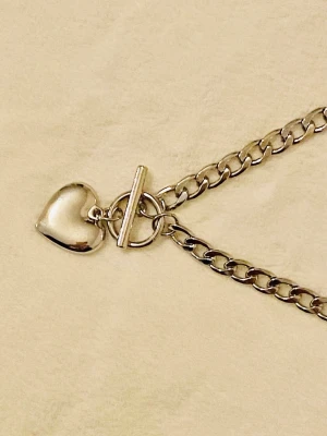 Silverfärgat halsband med hjärthänge - Snyggt halsband i silverfärg med grov kedja och ett blankt hjärthänge. Halsbandet har ett toggle-lås framtill som ger en trendig touch. Perfekt accessoar för att lyfta din outfit med en enkel men stilren detalj.