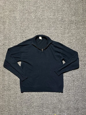 Mörkblå stickad tröja med halvzip - Hej! Säljer denna snygga mörkblå stickad tröja med halv dragkedja i kragen. Tröjan har långa ärmar och ribbade muddar vid ärmslut och nederkant. Storlek: 146/152 men det stämmer riktigt inte (modellen på bilden är 168 och den sitter perfekt). Perfekt för lager på lager och enkel att matcha med olika outfits. Vid storleksfundering eller intresse är det bara att höra av sig!!