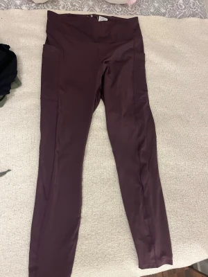 Vinröda tights från Ronhill - Säljer ett par vinröda tights från Ronhill/Staidium.  De har hög midja, smal passform och praktiska sidofickor. Perfekta för löpning eller gymmet, tillverkade i ett stretchigt funktionsmaterial som andas.