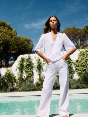 Vit blus med broderade ärmar - Stilren vit blus med v-ringning och trekvartsärmar. Ärmarna har broderade detaljer och lätt utsvängd form. Perfekt till både jeans och kostymbyxor. Tillverkad i ett lätt och luftigt 100% bomull. Aldrig använd, skulle kunna stryka till den innan jag postar. 