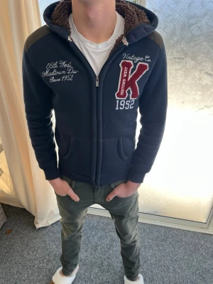 Mörkblå hoodie med brodyr och foder - Mörkblå hoodie med mörk brunt as skönt foder på insidan. Även i armarna är det fodrat. Skicket är riktigt bra och den är så otroligt skön och ha på sig. Personen på bilden är 183 cm lång Skicka gärna prisförslag.  