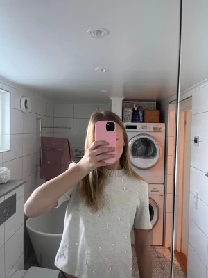 Ljusgrå topp med pärlor - Supersöt ljus beige topp med korta ärmar och rund halsringning och pärlor. Använd väldigt få gånger.