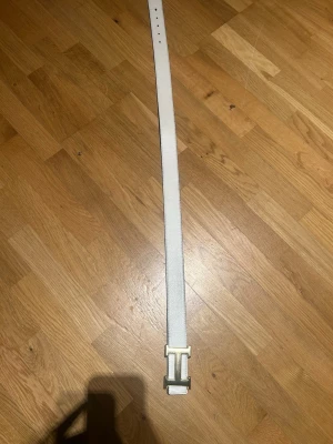 Vändbart vitt och svart skärp med H-spänne - Snyggt vändbart bälte i vitt och svart med ett stort H-format metallspänne. Perfekt accessoar för att lyfta vilken outfit som helst. Bältet har en stilren design och är gjort i skinn. 100cm långt. 