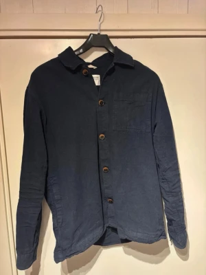 Mörkblå skjorta med träknappar - Snygg mörkblå skjorta från Selected homme i mjuk bomull i topp skick. Priset är diskuterbart.
