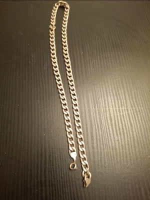 Kedjehalsband i silverfärg - Säljer ett stilrent halsband med grov kedja i silverfärgad metall. Halsbandet har en klassisk karbinhake och känns både tungt och rejält. Perfekt för dig som gillar en enkel men ändå statement look. Passar till många olika stilar och är lätt att matcha.
