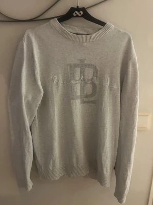 Grå sweatshirt från Bondelid - Säljer en stilren grå sweatshirt från Bondelid med broderad logga och text på bröstet. Tröjan har rund halsringning, ribbade muddar vid ärmslut och nederkant samt en relaxed passform. Perfekt för en casual look.