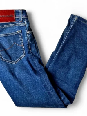 Jacob Cohen jeans - Snygga blå jeans från Jacob Cohen med klassisk femficksmodell och raka ben. Jeansen har kontrastsömmar och en läderpatch med logga bak i midjan. Tillverkade i slitstark denim som ger en tidlös look.