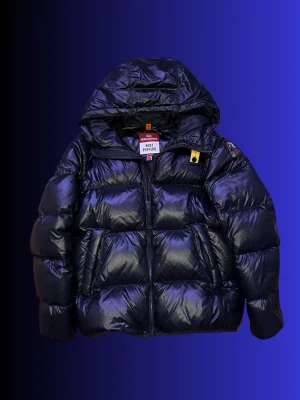 Mörkblå pufferjacka från Parajumpers - ÄKTA:  Snygg mörkblå pufferjacka från Parajumpers med glansig finish och stor huva. Jackan har dragkedja framtill, två sidofickor och en gul detalj vid halsen. Perfekt för kalla vinterdagar och riktigt trendig look.