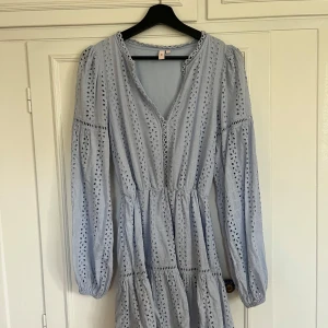 Ljusblå klänning - Superfin somrig ljusblå klänning från Gina Tricot med broderade detaljer och v-ringning. Slutsåld och finns inte längre på hemsidan. Långärmade puffärmar med resår vid handlederna. Helt ny, aldrig använd, som ny kostade den 600kr❣️