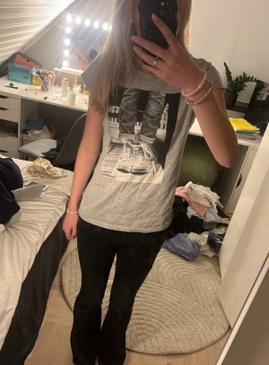 Grå Converse t-shirt med tryck - Säljer en grå t-shirt från Converse med ett stort svartvitt tryck framtill som visar ett par sneakers. T-shirten har korta ärmar och en klassisk passform. Perfekt för dig som gillar streetstyle och vill ha en enkel men snygg look. säljer den då den inte kommer till användning, kontakta mig om ni har frågor 💕