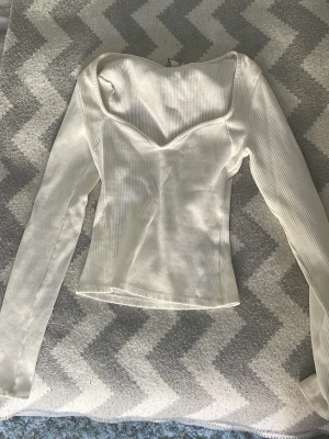 Vit topp - Supersnygg vit ribbad topp från Nelly med lång ärm och en trendig sweetheart-ringning. Figurnära passform som framhäver siluetten och ger en stilren look. Perfekt att styla med jeans eller kjol för en fräsch outfit.💕💕