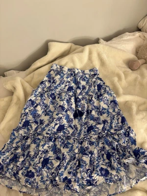 Långkjol med volang - Säljer en långkjol med blått och vitt blommönster. Fin till sommaren och säljer för den tyvärr är för kort för mig som är 163!🩵☀️