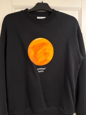 Svart sweatshirt Off-White Venus - Cool svart sweatshirt från Off-White med stor orange cirkel på bröstet och texten 'Off-White™ ©2013'. På ryggen står det 'ON THE GO' 