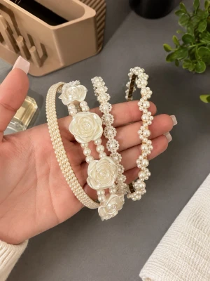 Pärlbeströdda diadem med blommor - Tre eleganta diadem i pärlvit färg, dekorerade med små pärlor och detaljerade blommor i plast. Perfekta för att ge en romantisk och lyxig touch till din look. Passar dig som gillar söta accessoarer med mycket detaljer.