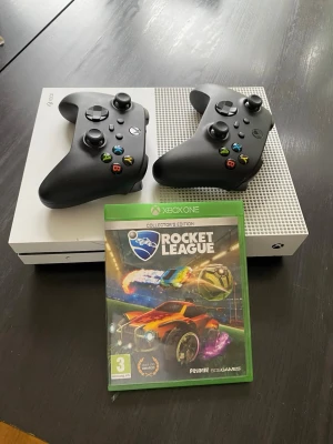 Xbox One S med två kontroller - Mycket bra skick. Säljer en vit Xbox One S med två svarta trådlösa handkontroller. Rocket League för Xbox One ingår. Perfekt för dig som vill ha bra kvalité för lite pengar.