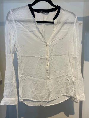 Vit blus - En vit blus med små guldknappar fram och längst ut vid armarna. Zara, storlek M.