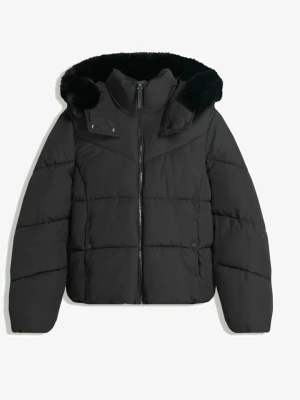 Svart pufferjacka med fuskpäls - Snygg svart pufferjacka med dragkedja framtill och avtagbar huva med mjuk fuskpäls. Jackan har quiltad design och hög krage som skyddar mot kyla. Perfekt för kalla vinterdagar och ger en trendig look.
