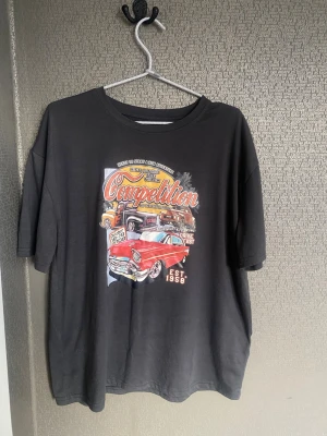 Svart t-shirt med biltryck - Cool svart t-shirt med färgglatt tryck av klassiska bilar och texten 'Competition' på framsidan. T-shirten har rund hals, korta ärmar och en relaxed passform. Perfekt för dig som gillar retrostil och streetwear. 